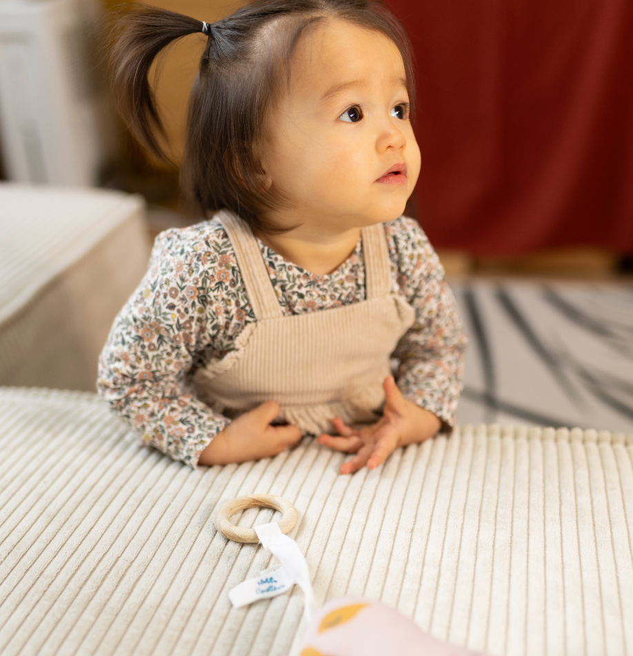 ambiance petite fille jouant avec son anneau de dentition bois et tissu motif hibou rouge terracotta Carotte & Cie