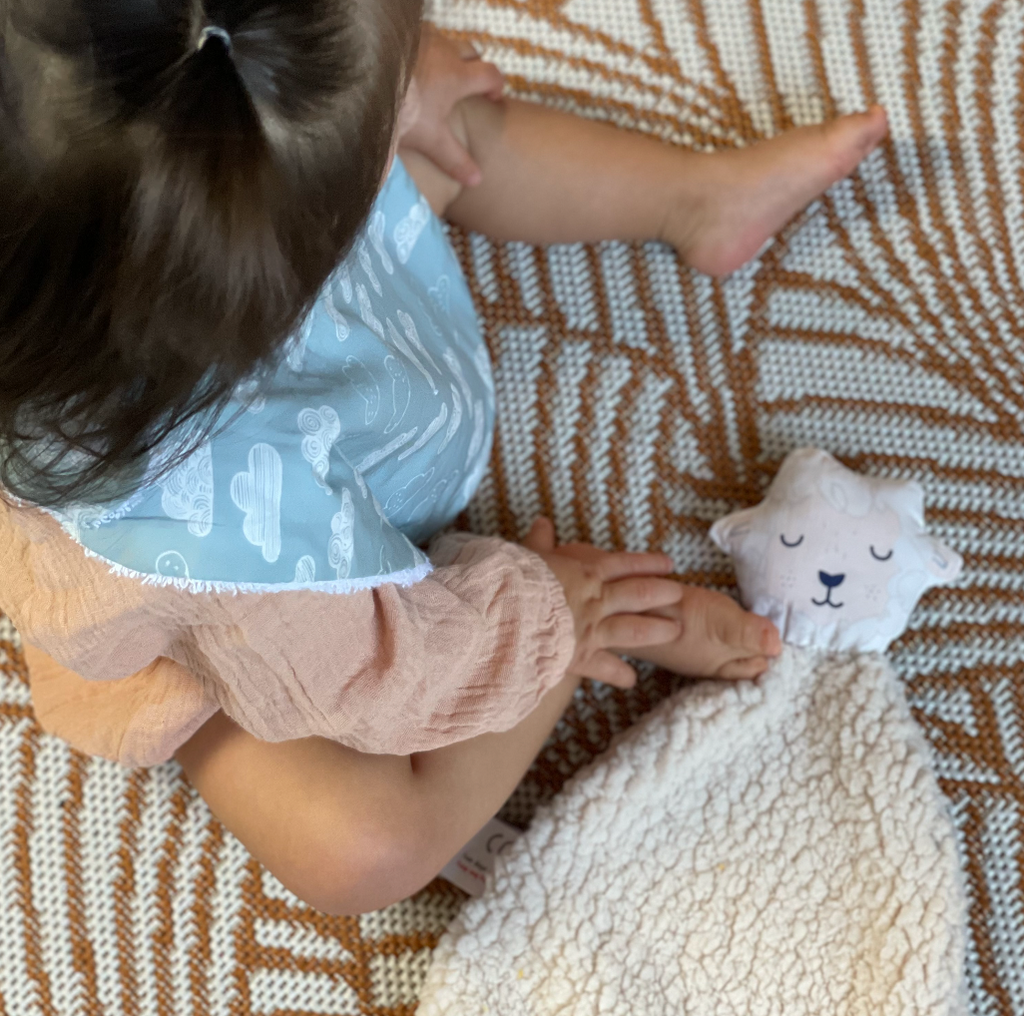 bébé jouant avec son doudou teddy beige motif mouton blanc et et beige Carotte & Cie