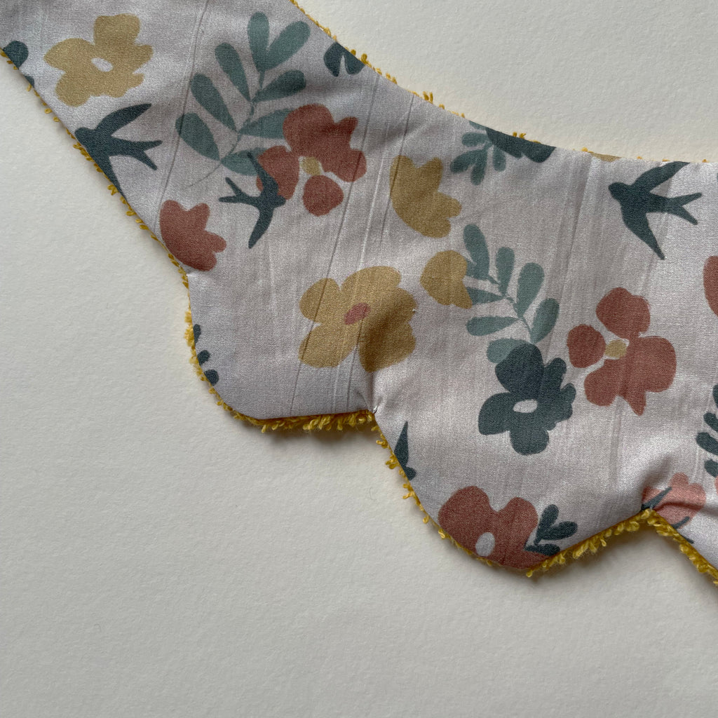détail du motif duu mini bavoir forme fleur pour les dents de bébé motif printemps fleurs fond rose pâle Carotte & Cie