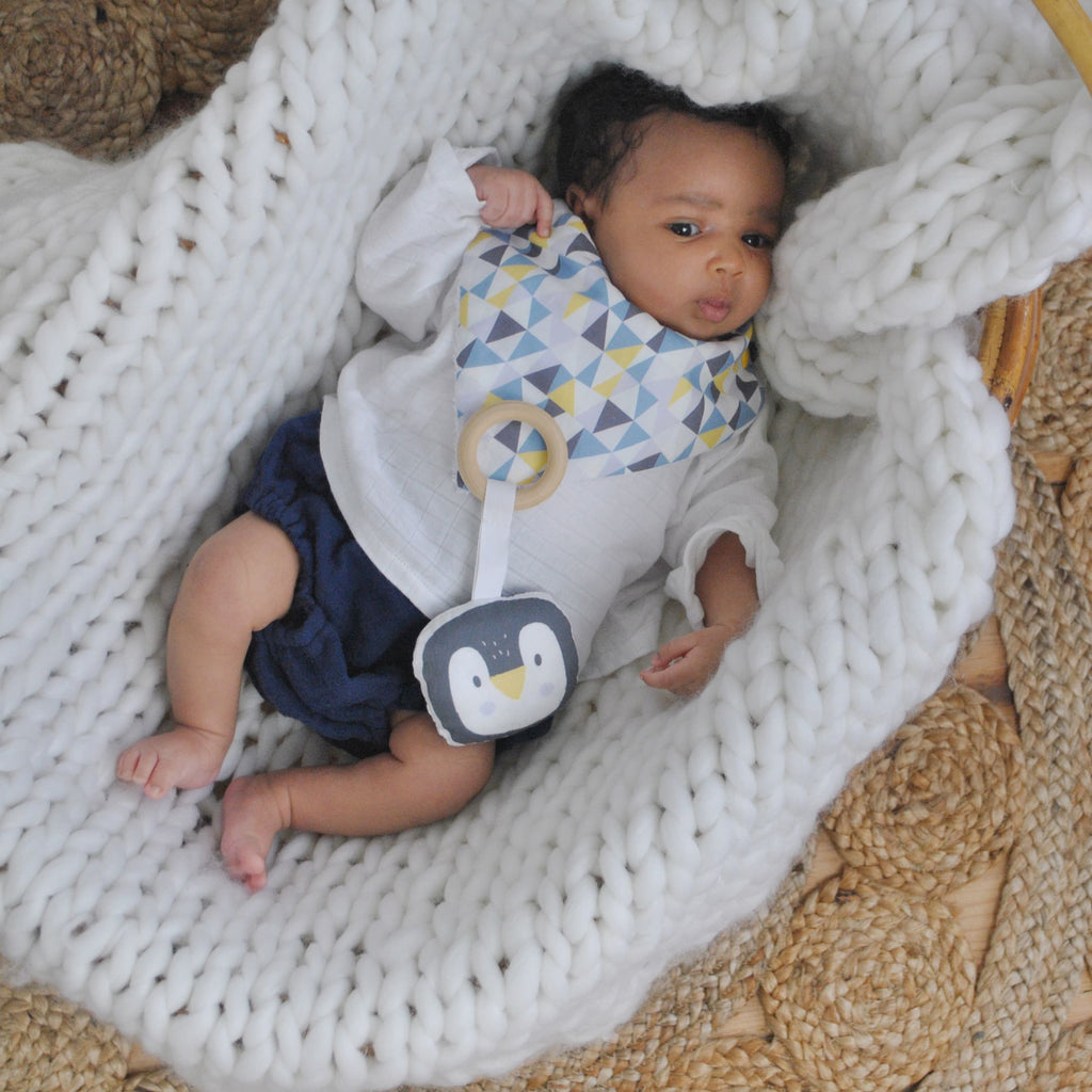 bébé porte un mini bavoir forme fleur pour les dents de bébé motif iceberg triangles bleu, gris et jaune Carotte & Cie