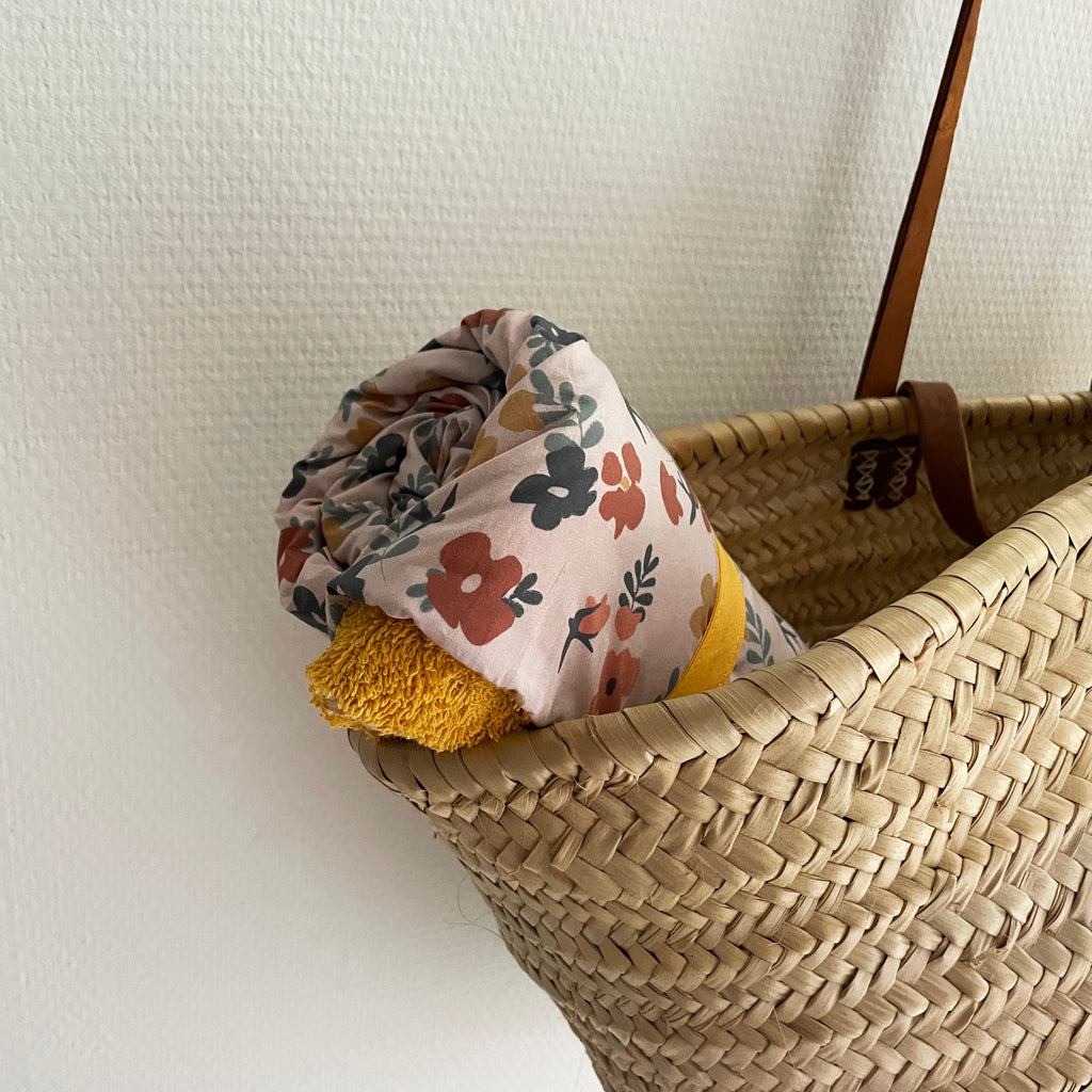 couverture nomade pouvant servir de tapis à langer, couverture, d'appoint, serviette de bain pour bébé motif printemps avec fleurs multicolores sur fond rose pâle dessiné et fabriqué en France par Carotte & Cie