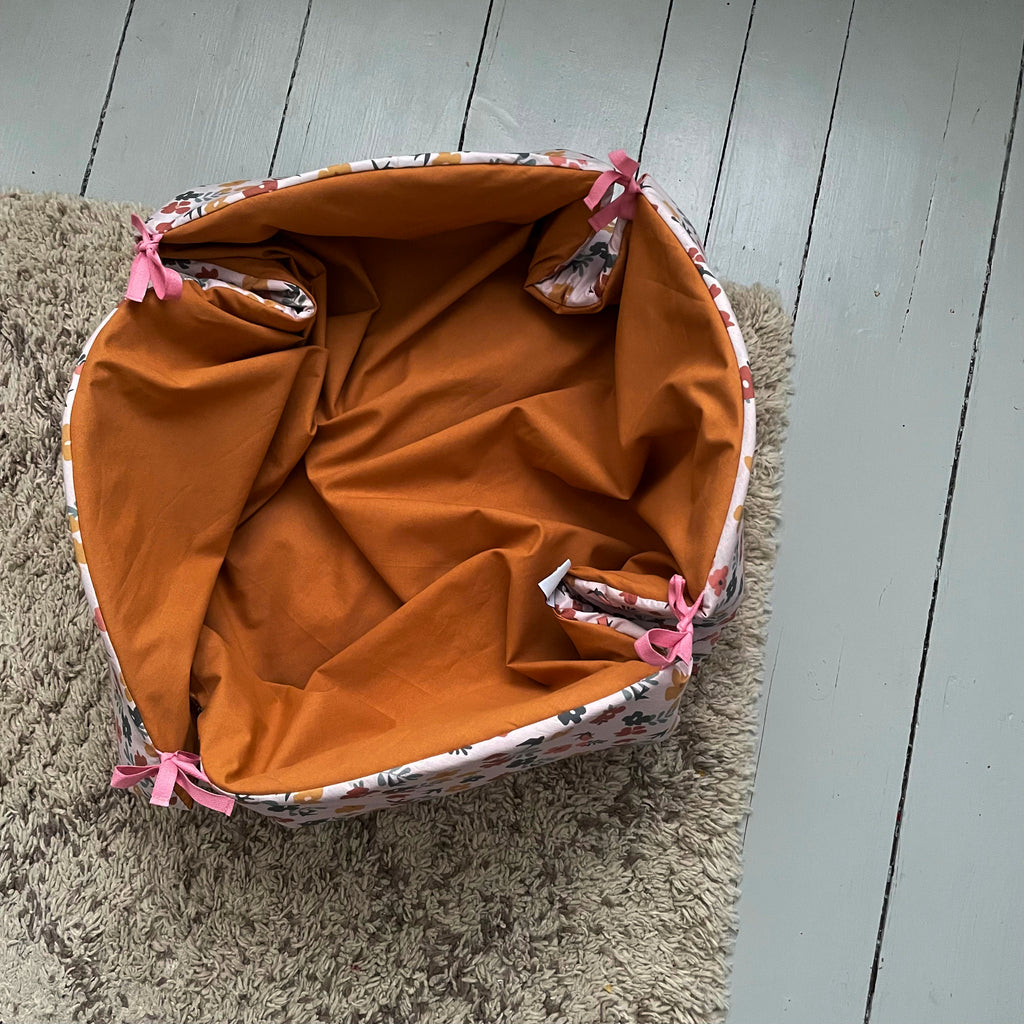 détail intérieur camel du tapis de jeu rond transformé en panier moelleux avec liens pour le transformer en panier de rangement pour jouets motif Printemps fond rose Carotte & Cie