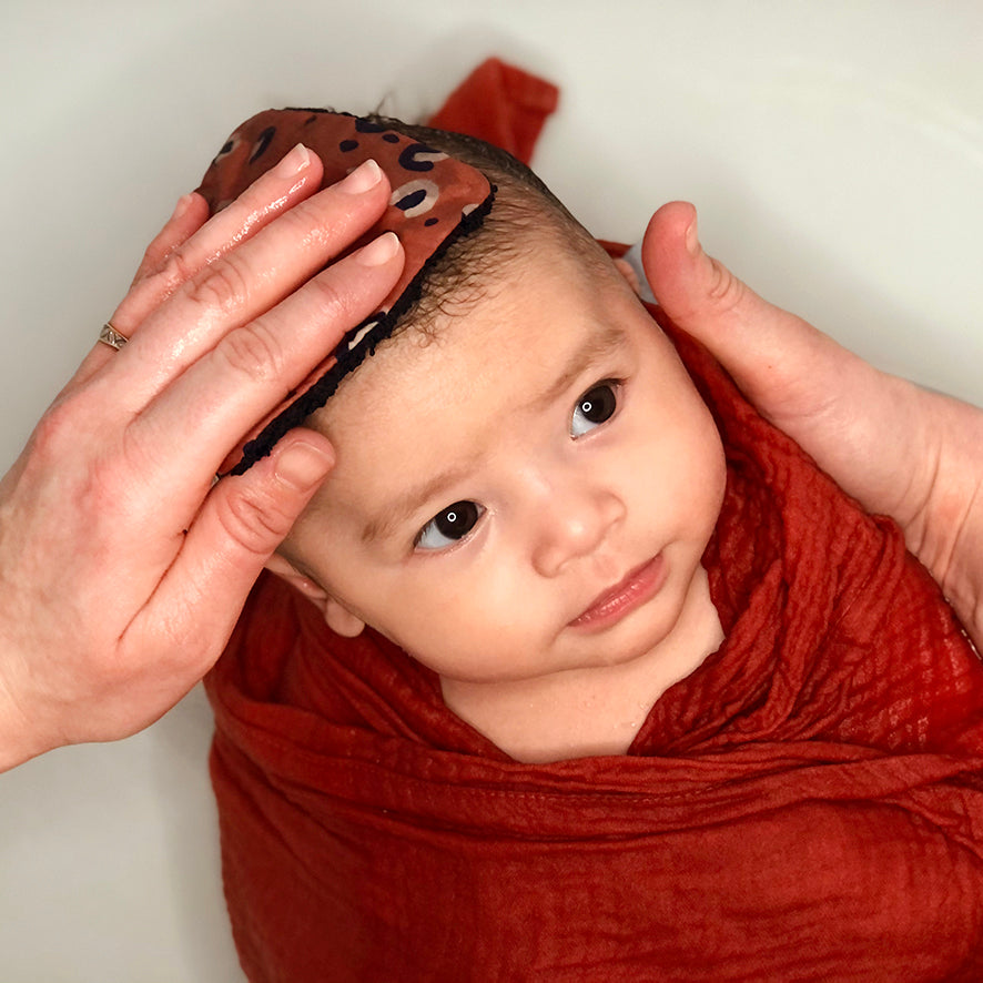 bébé emmitouflé dans son maxi lange uni en double gaze de coton oekotex rouge terracotta Carotte & Cie