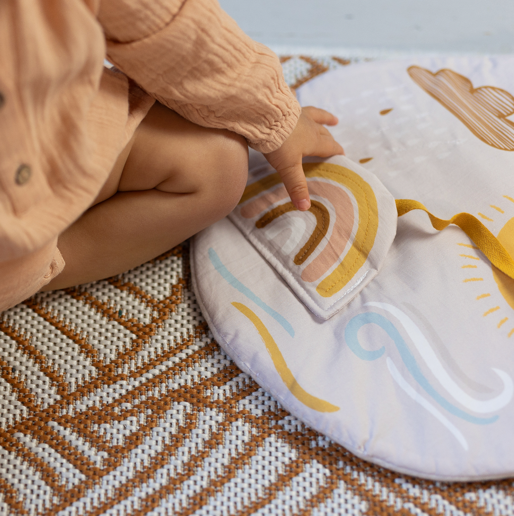 bébé joue avec son tableau d'éveil en tissu aux motifs inspirés de la météo dessiné et fabriqué en France par Carotte & Cie