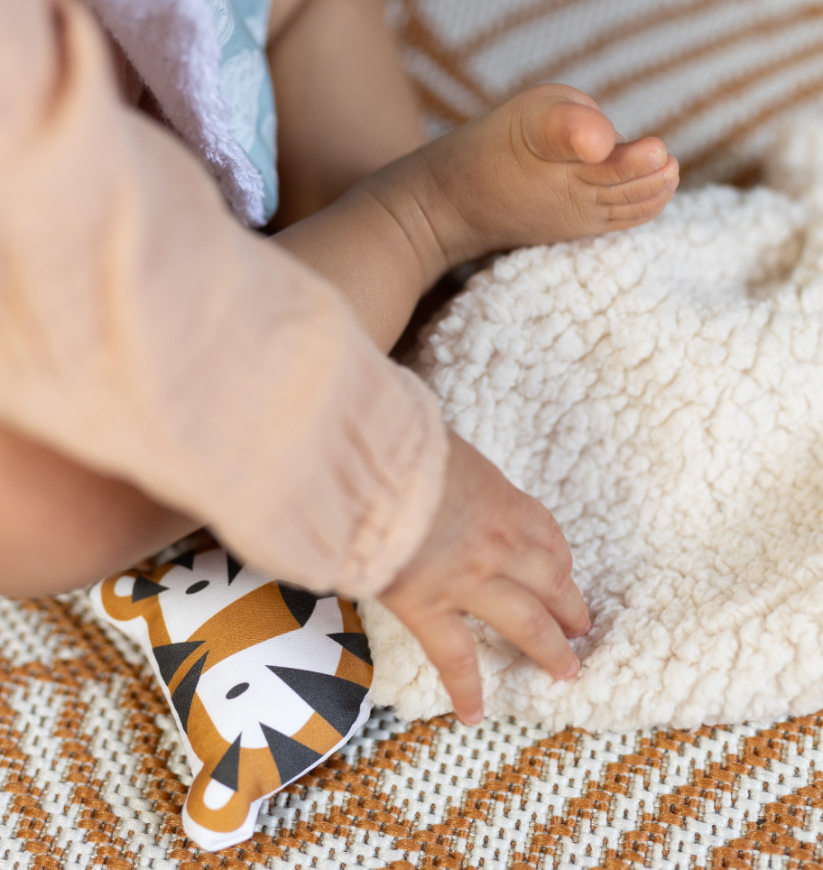 bébé jouant avec son doudou teddy beige motif tigre camel et marrone fabriqué en France Carotte & Cie