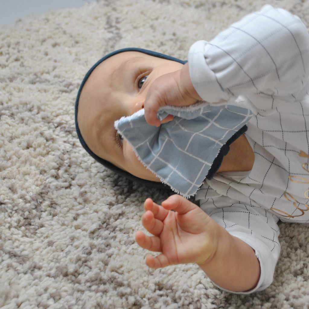 Bébé joue avec une lingette de son lot de 10 lingettes lavables format carré motif exclusif carreaux bleu et éponge blanche dessiné et fabriqué en France par Carotte & Cie