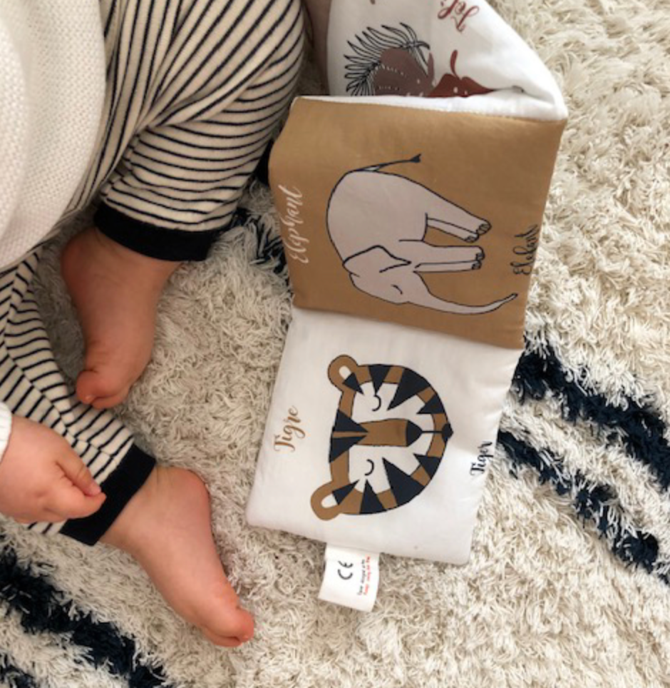 bébé joue avec son livre d'éveil animaux de la savane une face coloriée et une autre noir et blanc pour l'éveil de bébé dessiné avec amour par Carotte & Cie