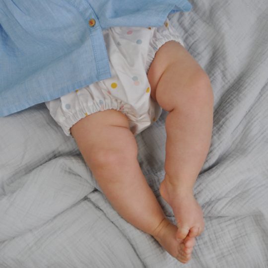 bébé porte un bloomer bébé en coton biologique motif confettis multicolores sur fond beige rosé Carotte & Cie