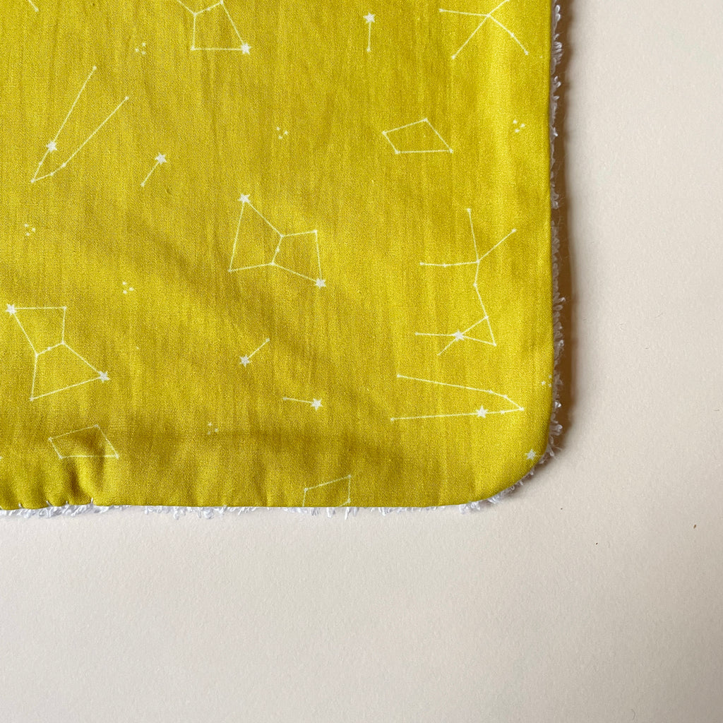 détail du motif du grand bavoir motif constellations jaune moutarde et dos éponge blanche Carotte & Cie