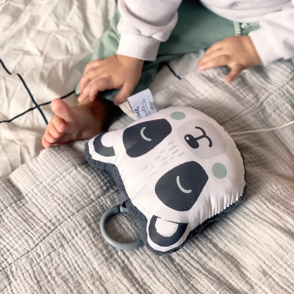 bébé joue avec son mini coussin musical nomade tête de panda noir et blanc et vert eucalyptus Carotte & Cie