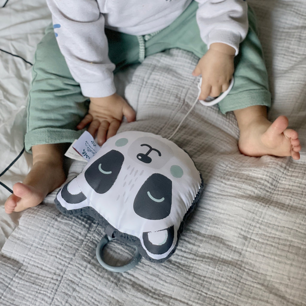 bébé joue avec son mini coussin musical nomade tête de panda noir et blanc et vert eucalyptus Carotte & Cie