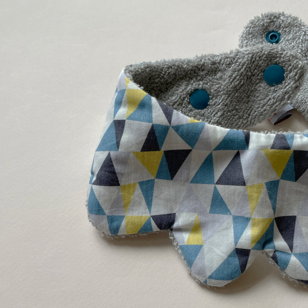 détail du motif du mini bavoir forme fleur pour les dents de bébé motif iceberg triangles gris, jaune et bleu Carotte & Cie
