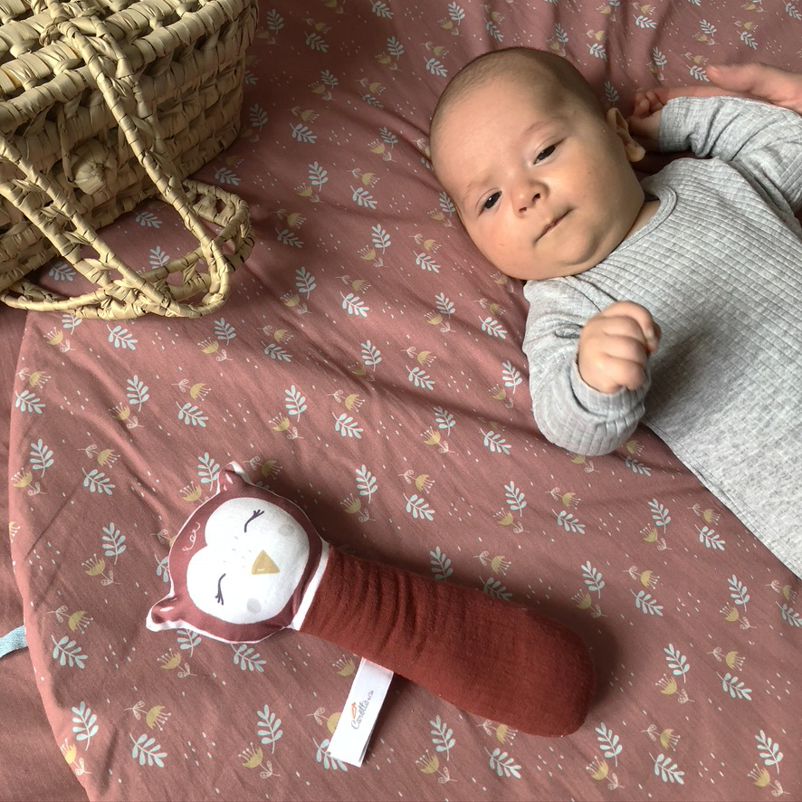 Bébé joue avec son hochet gling gling hibou en coton biologique et gaze de coton oekotex pour bébé rouge terracotta Carotte & Cie