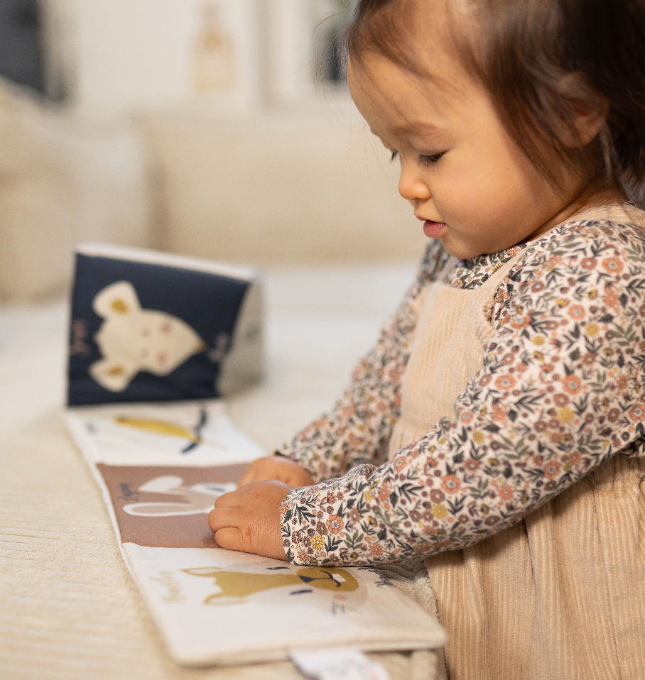 bébé jouant avec son livre d'éveil en coton biologique motif Animaux de compagnie exclusif Carotte & Cie 