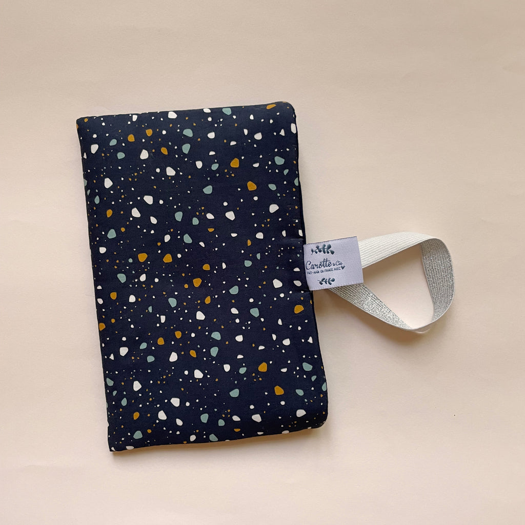 Petite pochette de protection pour livres format poche rembourrée et avec un élastique de maintien; Motif Granite terrazzo fond bleu marine dessiné et fabriqué avec amour par Alexandra, créatrice de Carotte & Cie. Idéal cadeau de fête des mères.