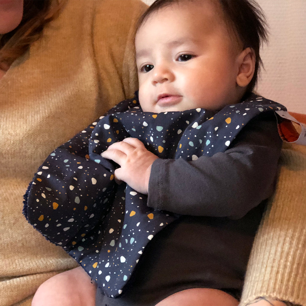 bébé porte un bavoir pour les repas de bébé motif exclusif granite Terrazzo bleu marine Carotte & Cie