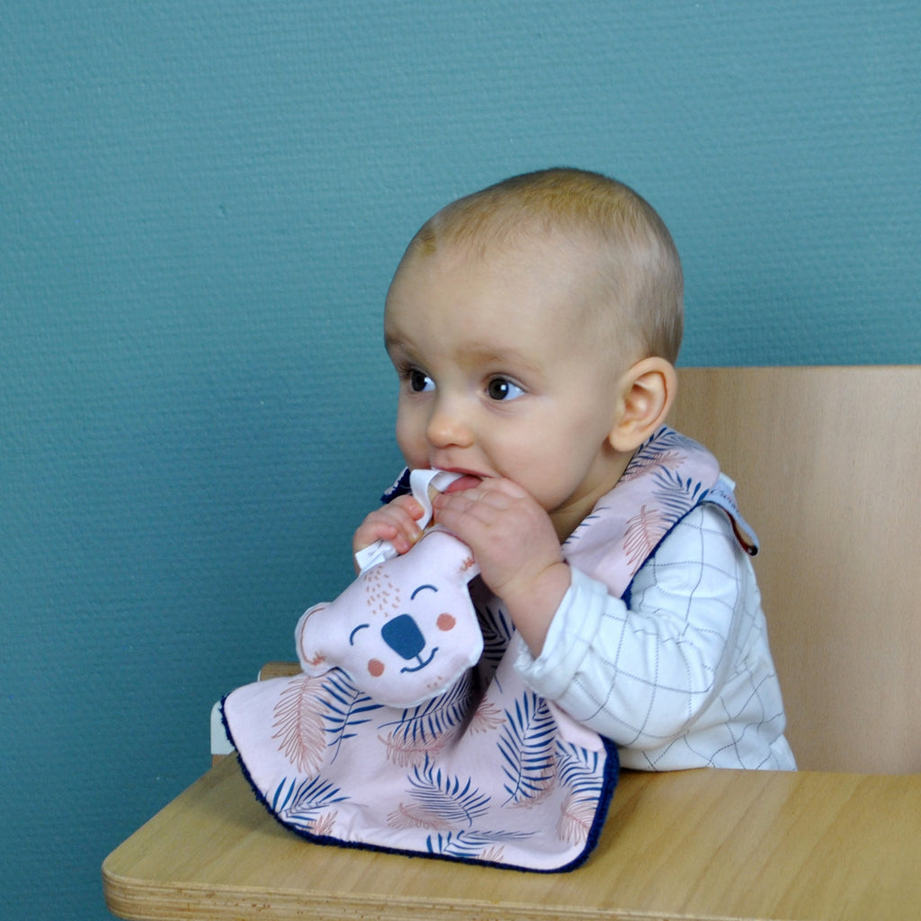 bébé porte un bavoir pour les repas de bébé motif exclusif feuillage rose et bleu marine Carotte & Cie