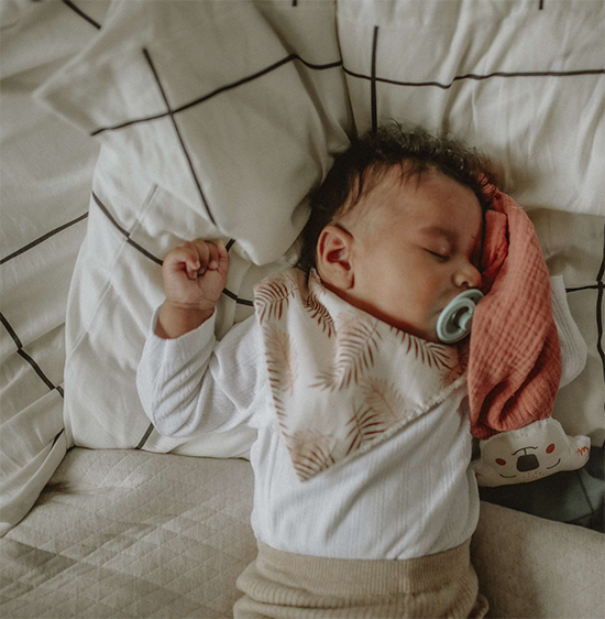 bébé dort avec son mini bavoir bandana pour les dents de bébé motif feuillage cuivré sur fond beige Carotte & Cie
