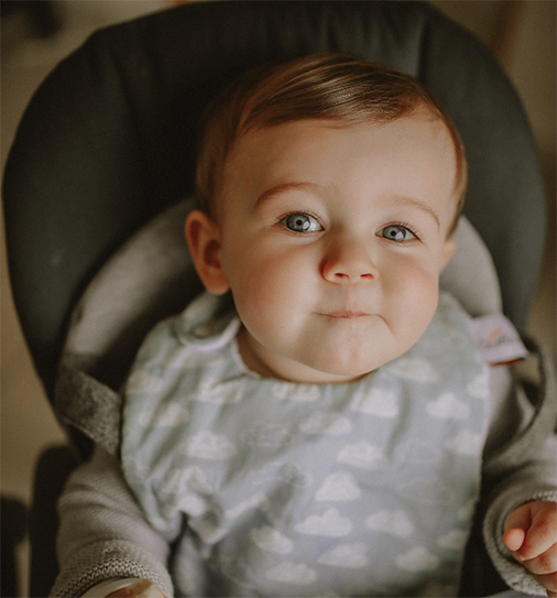 bébé porte un bavoir pour les repas de bébé motif exclusif nuages blancs sur fond bleu céladon Carotte & Cie