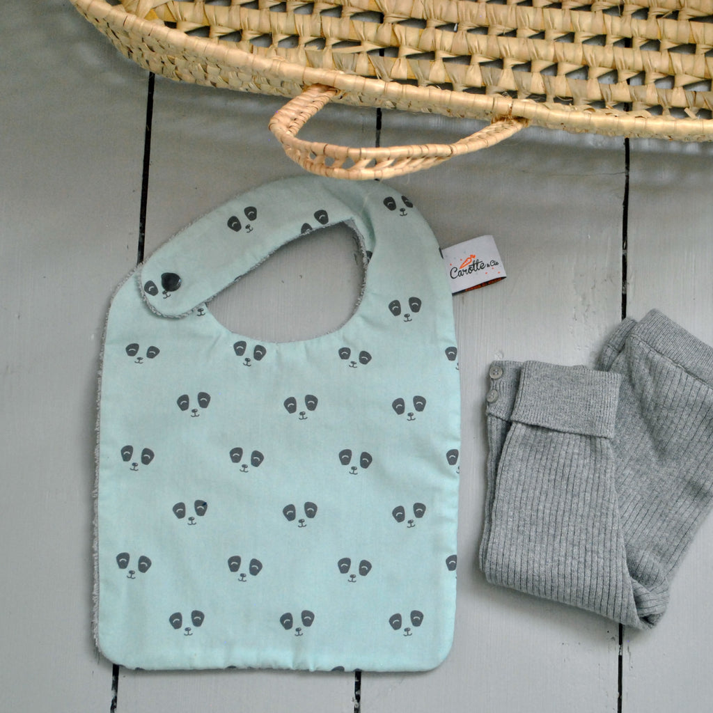 ambiance valise naissance avec un bavoir pour les repas de bébé motif exclusif panda gris sur fond vert pastel Carotte & Cie