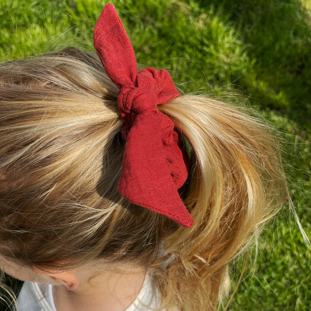 fillette portant le chouchou enfant en double gaze de coton rouge terracotta avec une grand noeud Carotte & Cie