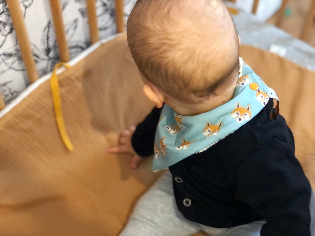 bébé porte un mini bavoir bandana pour les dents de bébé motif renards oranges sur fond bleu céladon Carotte & Cie