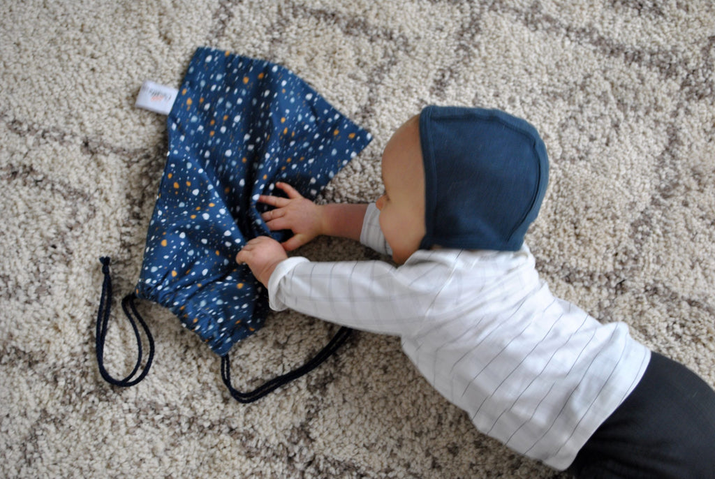 bébé joue avec son pochon en coton avec liens pour le goûter, le pyjama ou les jouets motif granite Terrazzo fond bleu marine Carotte & Cie