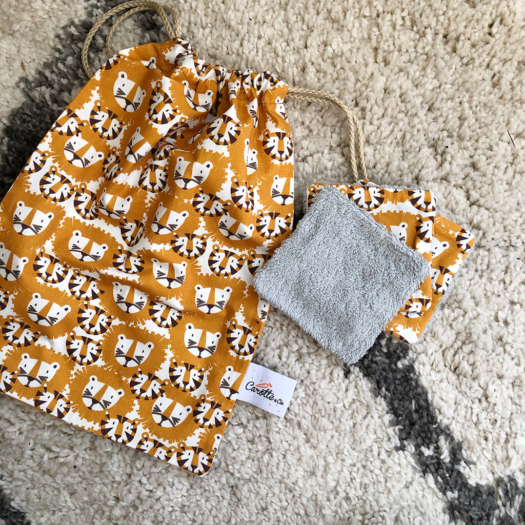 bébé range ses petites affaires dans son pochon en coton avec liens pour le goûter, le pyjama ou les jouets motif tigres et lions orange et marron Carotte & Cie